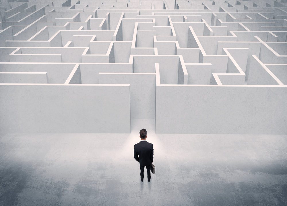 A good looking businessman with briefcase standing in front of white labirynth entrance about to make a decision concept